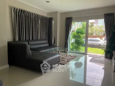 Modern living room with sleek black leather sofa and garden view