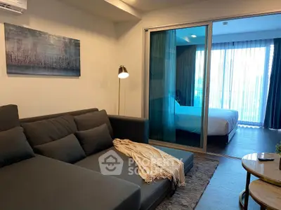 Modern living room with cozy sofa and view into stylish bedroom