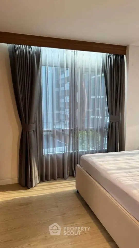 Spacious bedroom with large window and elegant curtains in modern apartment