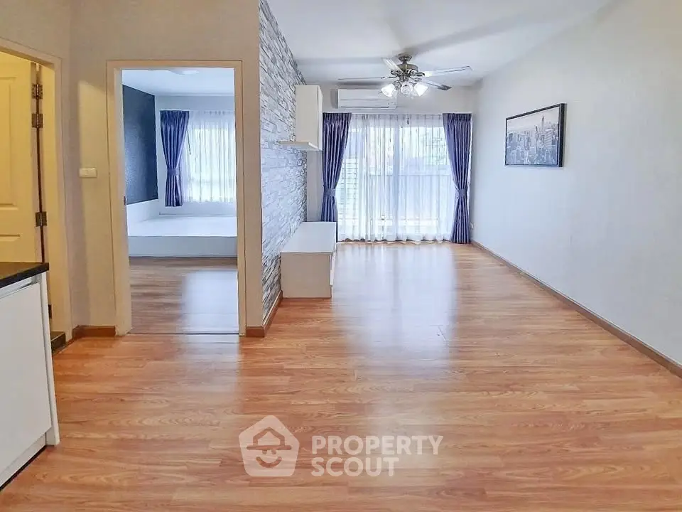 Spacious open-plan living area with wooden flooring and large windows for natural light.