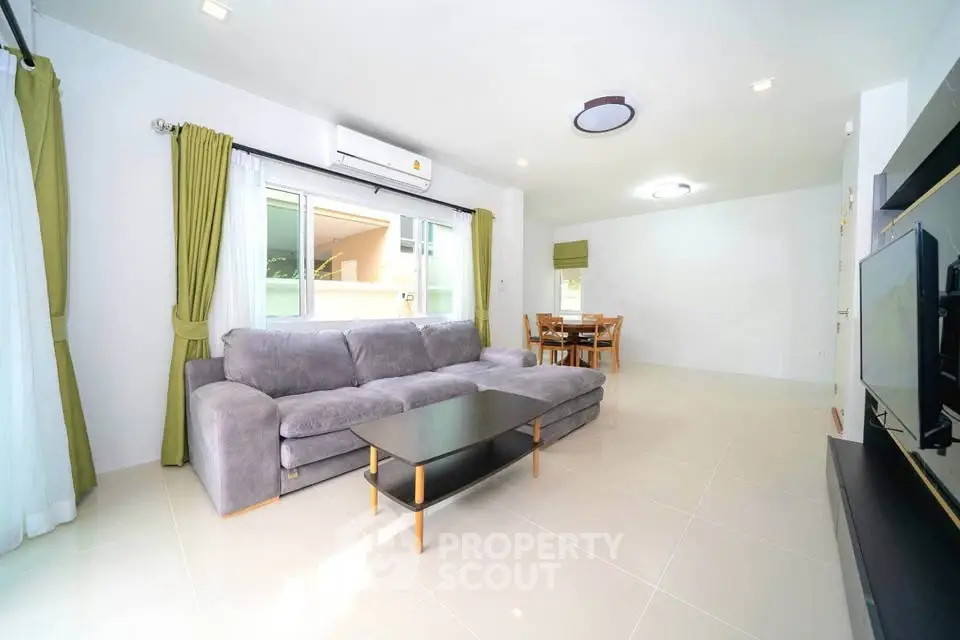 Spacious modern living room with large sofa and dining area, featuring natural light and stylish decor.