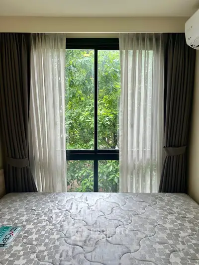 Cozy bedroom with large window and lush garden view, perfect for relaxation.