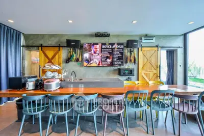 Modern kitchen with open layout, featuring a large island, colorful chairs, and a wall-mounted TV.