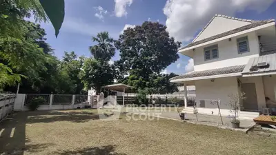 Charming suburban house with spacious garden and lush greenery under a clear blue sky.
