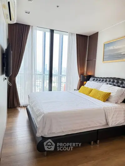Modern bedroom with city view, featuring elegant decor and large windows.