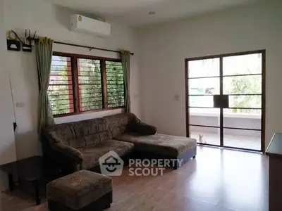 Spacious living room with large windows and comfortable seating, perfect for relaxation.