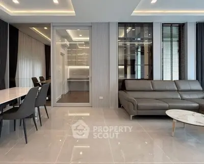Luxurious modern living room with sleek furniture and open dining area, featuring elegant lighting and contemporary design.