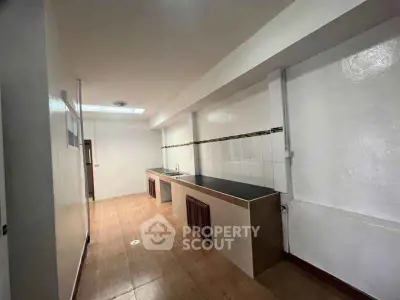 Spacious kitchen with sleek countertops and ample storage in modern apartment.