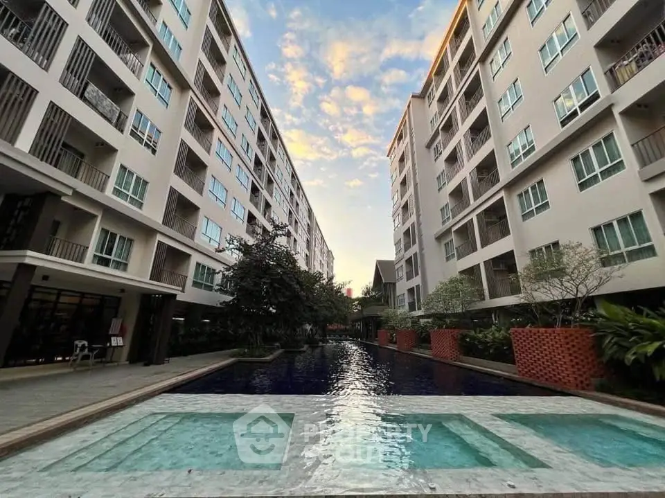 Modern apartment complex with a stunning central pool and lush landscaping.