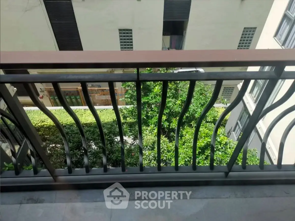 Charming balcony view with lush greenery in a modern apartment complex.