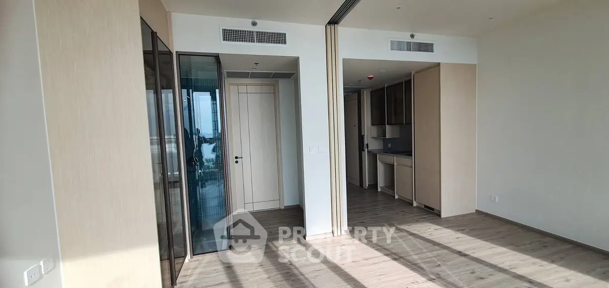 Modern apartment interior with open layout and wooden flooring, featuring a sleek kitchen area.