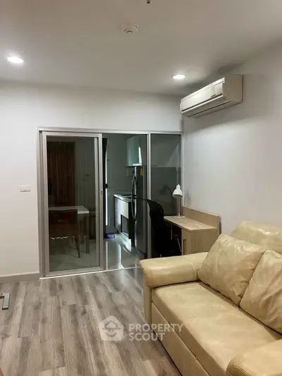 Modern living room with cozy sofa and sleek kitchen area in open layout apartment.