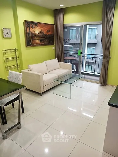 Modern living room with glass coffee table and balcony view in vibrant apartment.