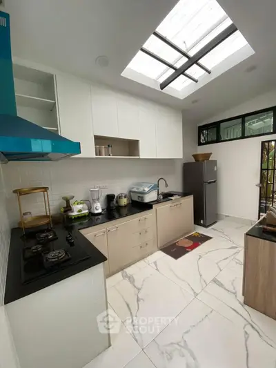 Modern kitchen with skylight, sleek cabinetry, and gas stove in a contemporary home.