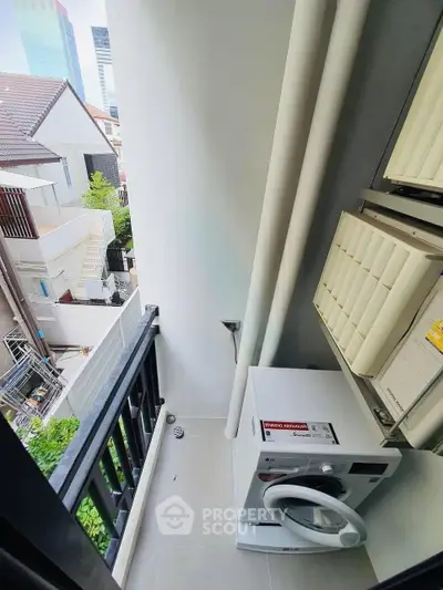 Compact balcony with washing machine and urban view, ideal for city living convenience.