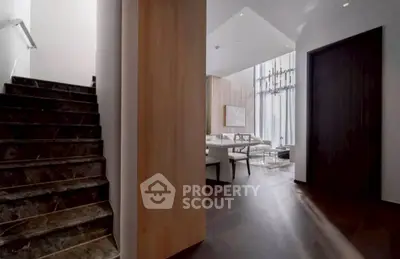 Luxurious modern interior with elegant staircase and spacious living area, featuring high ceilings and stylish decor.