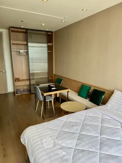 Modern bedroom with stylish decor and cozy seating area, featuring wooden flooring and elegant furnishings.