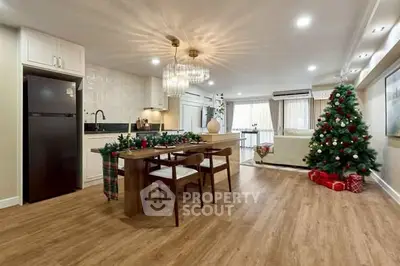 Spacious living room with festive decor and modern kitchen in open layout apartment.