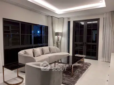 Elegant modern living room with plush gray sofa, stylish lighting, and large windows for natural light.