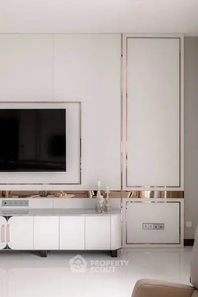 Luxurious modern living room with sleek white cabinetry and large flat-screen TV.