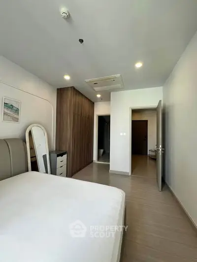 Spacious modern bedroom with sleek wooden flooring and built-in wardrobe