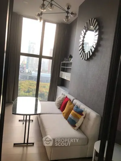 Stylish modern living room with large windows and city view, featuring a cozy sofa and decorative mirror.