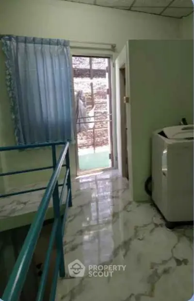 Compact laundry area with washing machine and marble flooring in modern apartment.