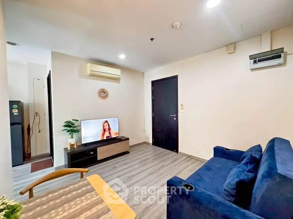 Modern living room with blue sofa, TV, and air conditioning in a cozy apartment.