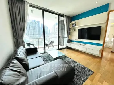 Modern living room with city view, featuring sleek black sofa, glass coffee table, and wall-mounted TV.