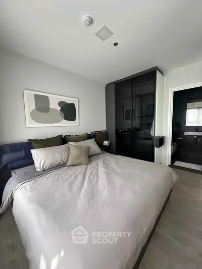 Modern bedroom with sleek design and stylish decor, featuring a comfortable bed and contemporary artwork.