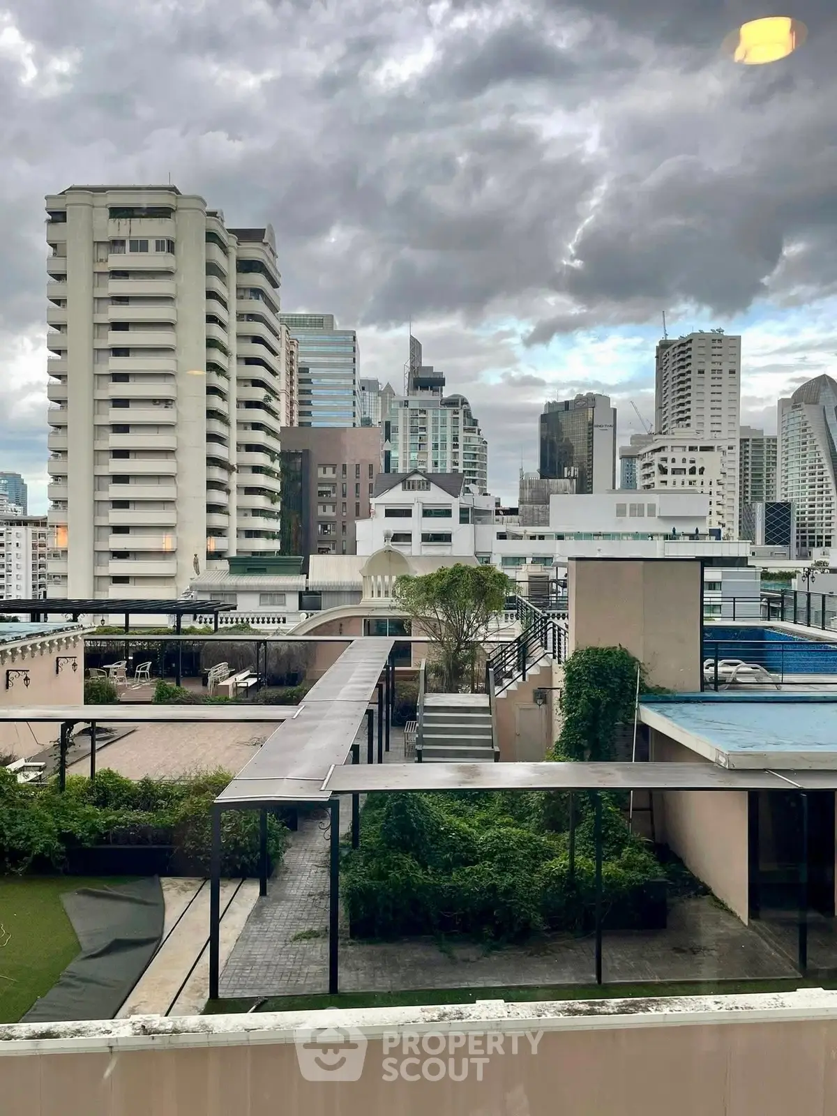 Stunning urban rooftop view with lush greenery and city skyline backdrop, perfect for modern living.