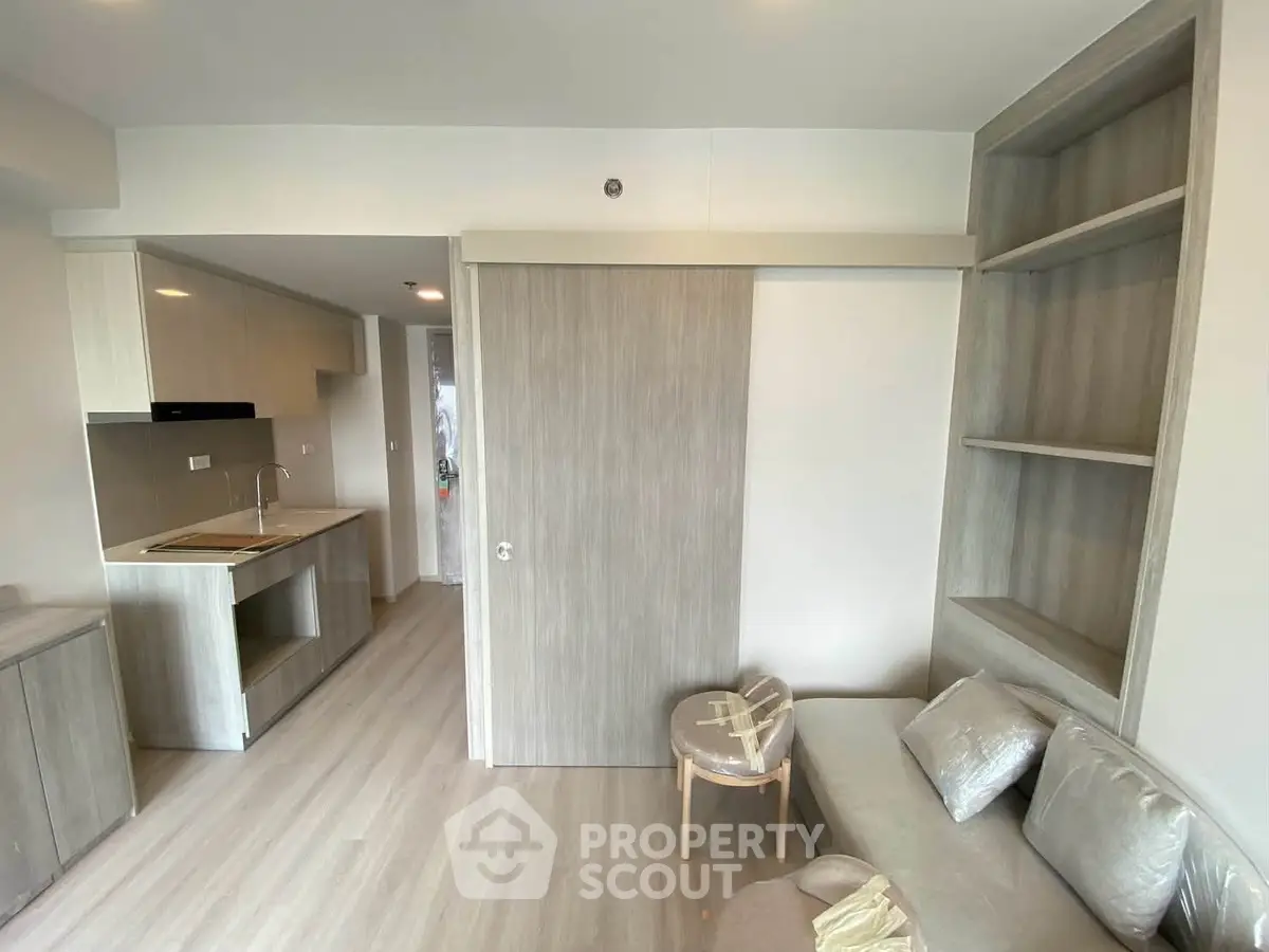 Modern living room with sleek built-in shelves and compact kitchen area