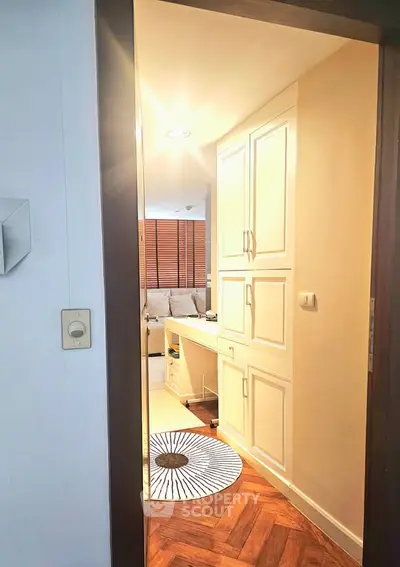 Charming hallway leading to a cozy living area with elegant parquet flooring and stylish cabinetry.