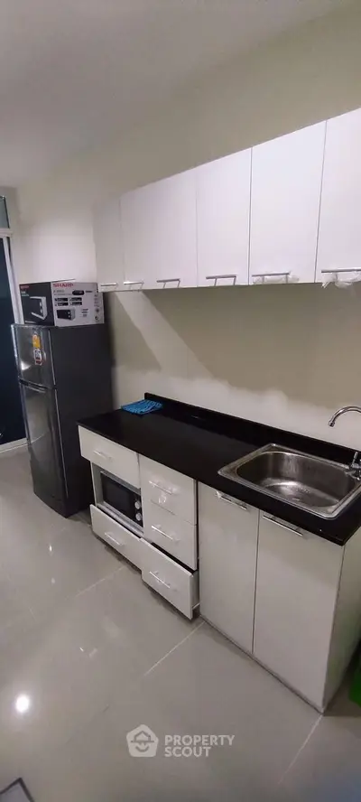 Modern kitchen with sleek cabinetry, stainless steel appliances, and glossy tile flooring.