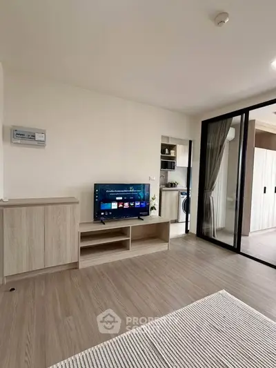 Modern living room with sleek wooden flooring and sliding glass doors leading to a balcony.