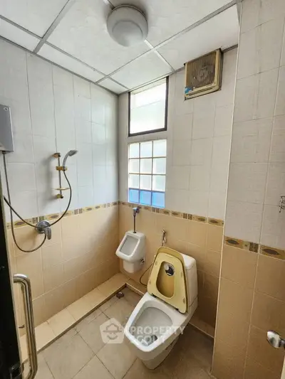 Spacious bathroom with modern fixtures and ample natural light, featuring a shower and toilet.