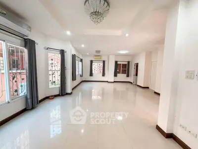Spacious and bright living room with elegant chandelier and large windows.