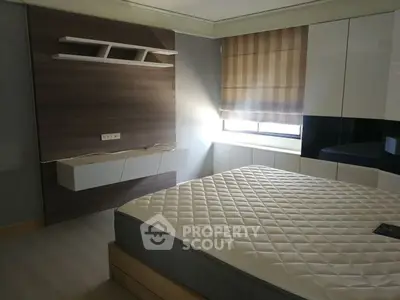 Modern bedroom with stylish wall paneling and large window for natural light.