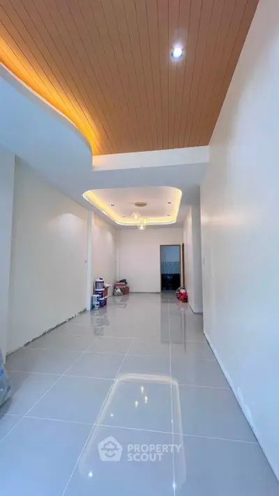 Spacious modern living room with elegant ceiling lights and glossy tiled flooring.