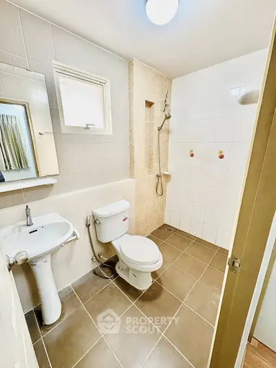 Modern bathroom with shower and toilet in a bright, tiled space.