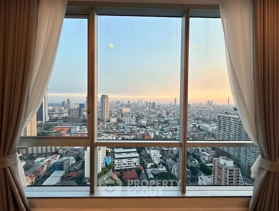 Stunning cityscape view from a high-rise apartment window with elegant curtains framing the skyline.