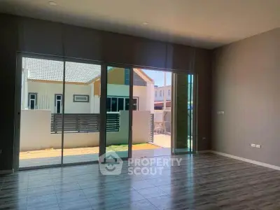 Spacious modern living room with large glass doors opening to a bright outdoor area.