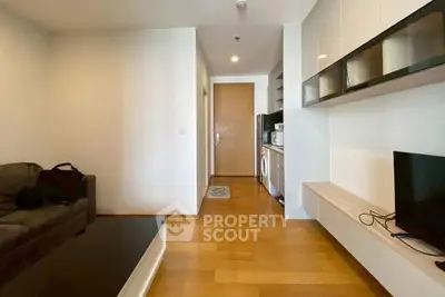 Modern living room with sleek furniture and integrated kitchen appliances in a cozy apartment.