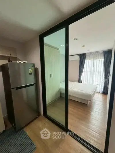 Modern apartment with sleek kitchen and cozy bedroom featuring mirrored sliding doors.