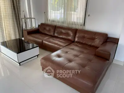 Spacious living room with elegant brown leather sectional sofa and modern coffee table.