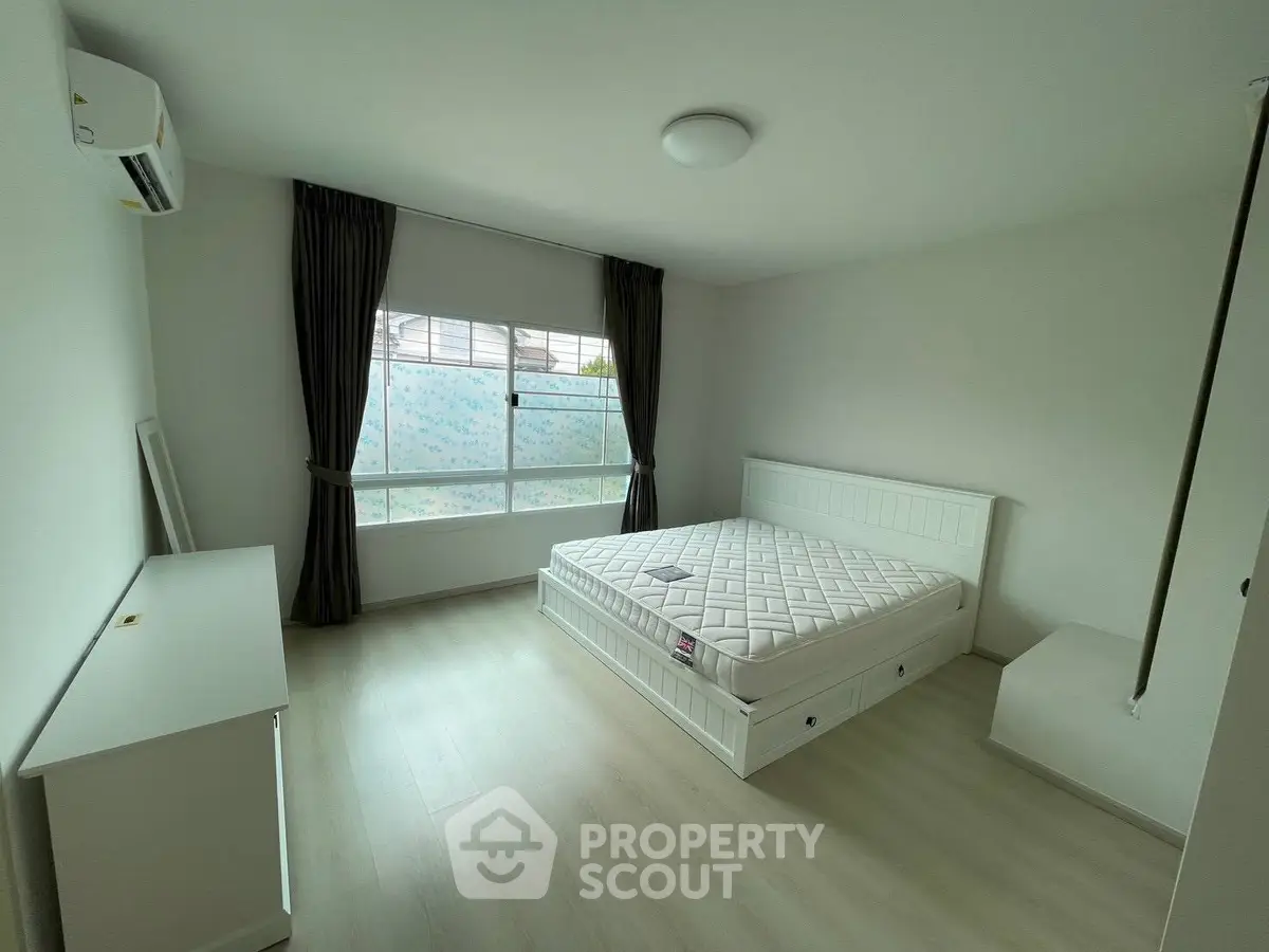 Spacious bedroom with large window and minimalist decor in modern apartment