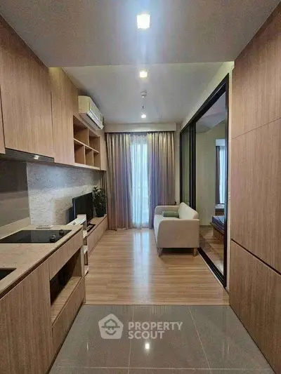 Modern open-plan kitchen and living room with wooden finishes and natural light.