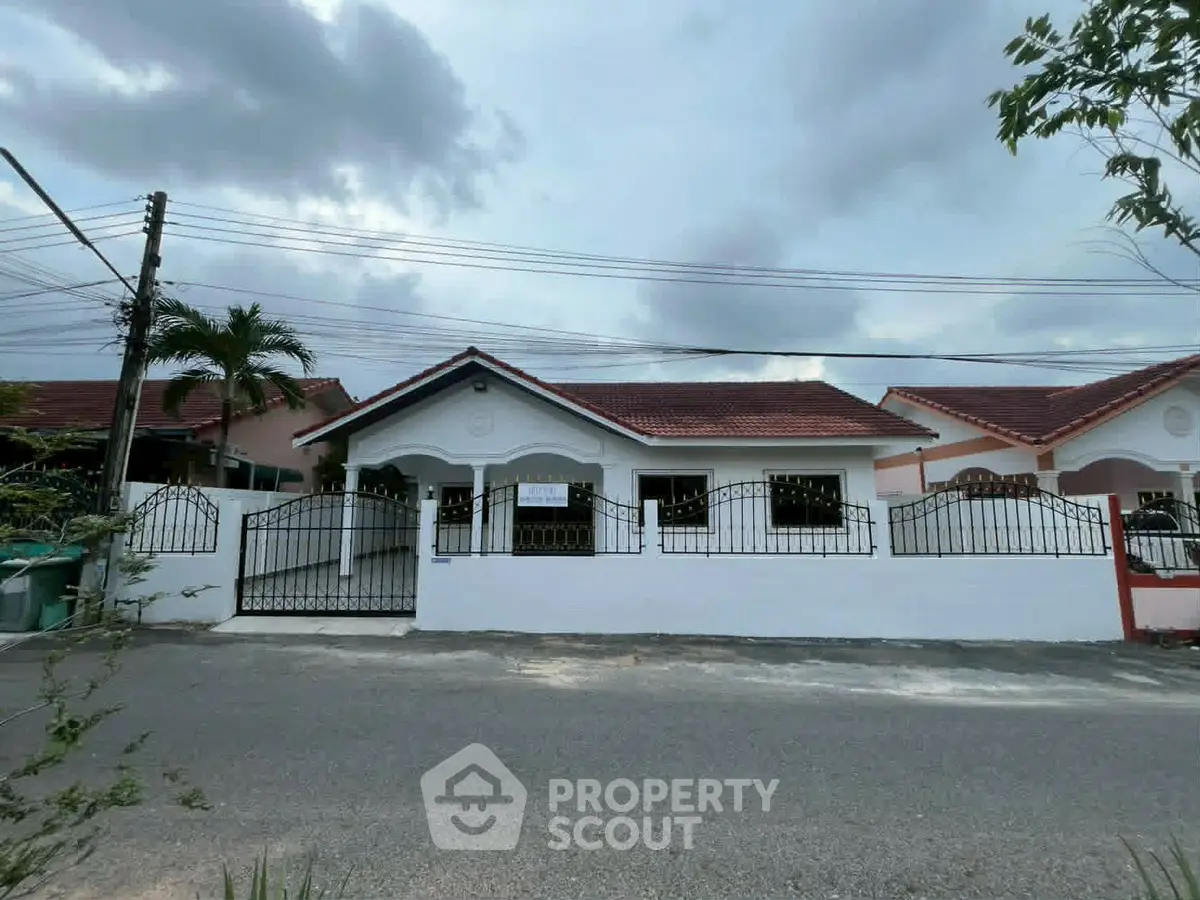 Charming single-story house with gated entrance and red-tiled roof in a serene neighborhood.
