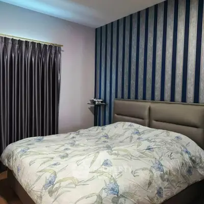 Elegant bedroom with floral bedding and stylish wallpaper, perfect for a cozy retreat.