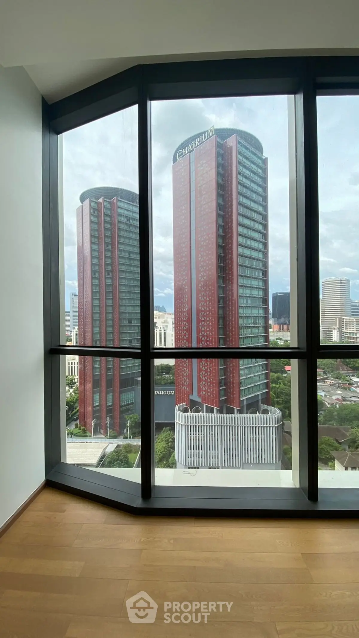 Stunning city view from modern high-rise apartment with floor-to-ceiling windows.
